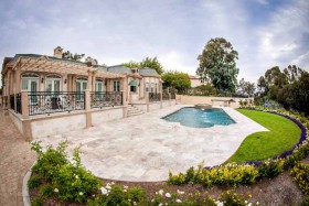 stone-paved-pool-area-with-house-and-landscaped-area